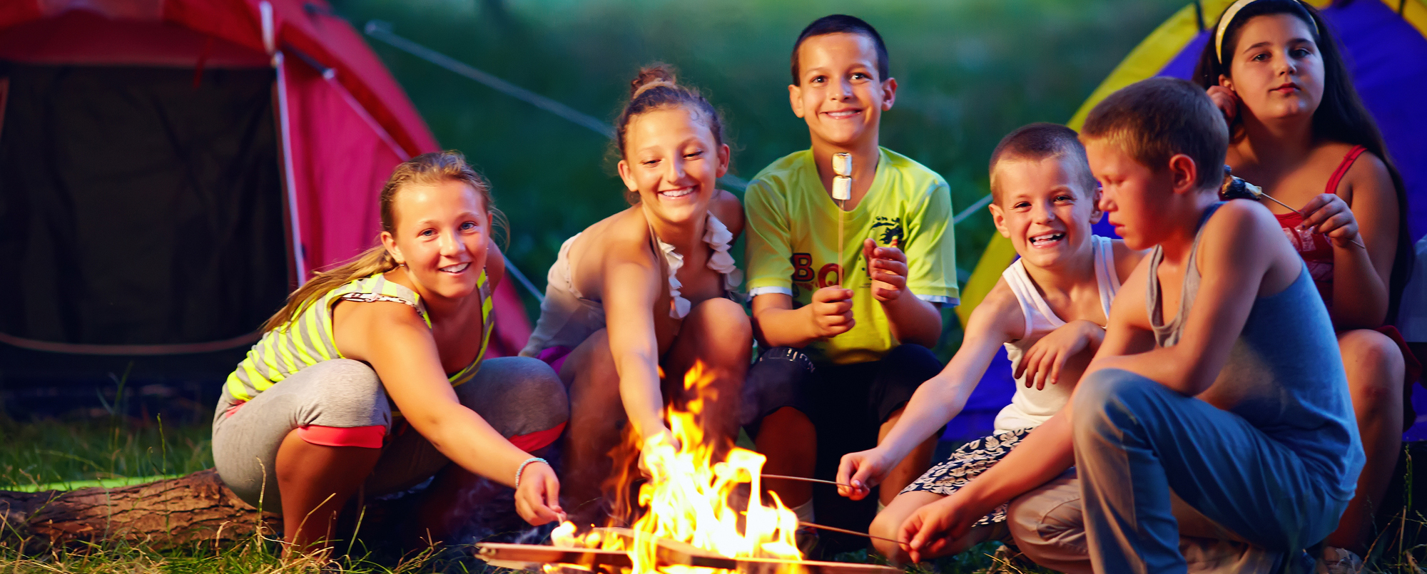 Kids smiling and toasting marshmallows over a fire