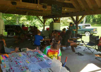 Kids sitting at picnic tables outside making crafts