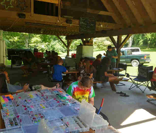 Kids sitting at picnic tables outside making crafts