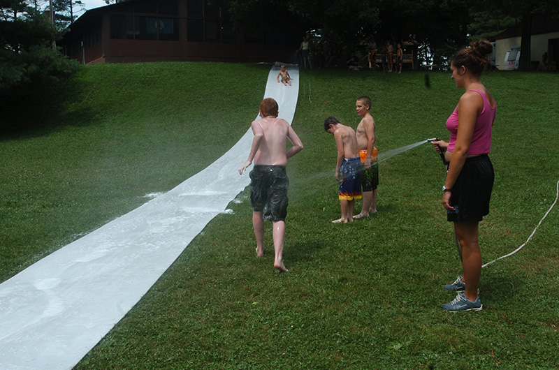 Campers playing on a slip-n-slide in the summer